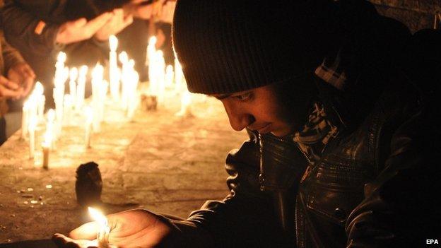 Pakistani mourner lights a candle to pray for the victims who were killed in an attack at the Army run school in Peshawar