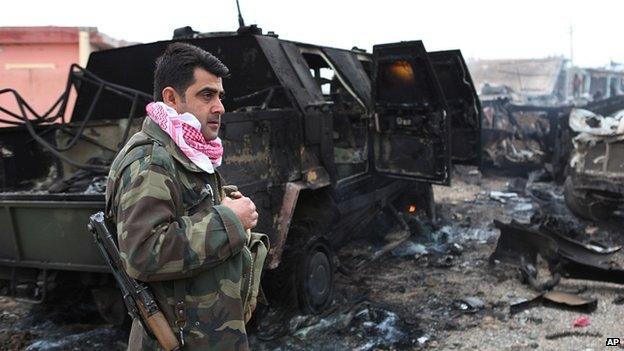 Kurdish fighter next to vehicle destroyed by IS during advance towards Mount Sinjar. 18 Dec 2014