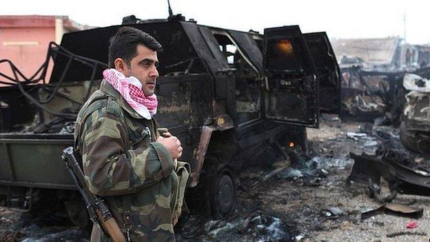 Kurdish fighter next to vehicle destroyed by IS during advance towards Mount Sinjar. 18 Dec 2014