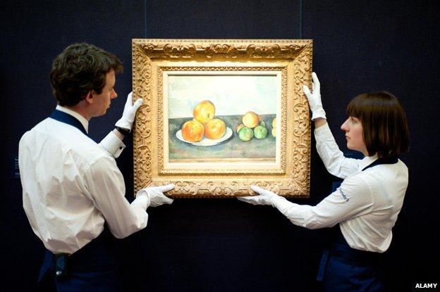 Sotheby's employees pose in front of 'Les Pommes' by Paul Cezanne