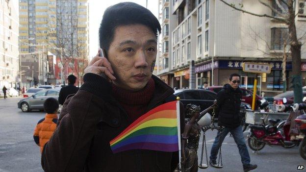 Yang Teng holds up a statue depicting a goddess of justice and a rainbow colour flag as he arrives to attend a court verdict in Beijing, China, Friday, Dec. 19,