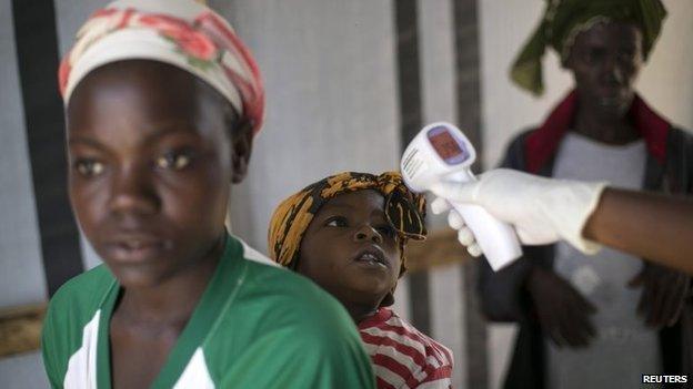 A health worker checks a girl's temperature