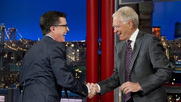 Stephen Colbert shakes late night host David Letterman's hand.