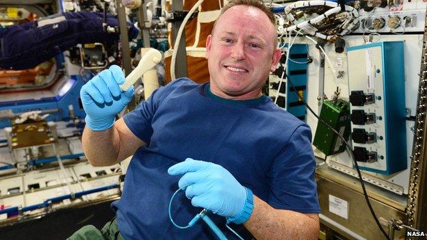 Commander Barry Wilmore on board the International Space Station, holding a 3D-printed ratchet