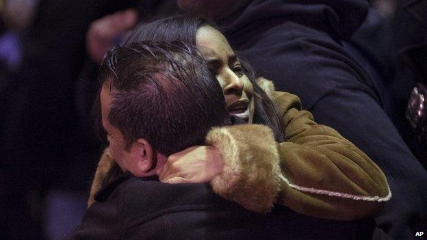 Mourners gather before the bodies of two NYPD police officers are transported to a hospital, 20 December, 2014