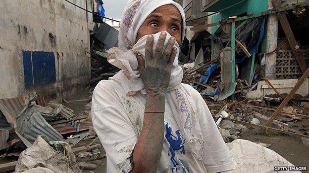 An elderly Indonesian woman stands in front of her damaged house in Banda Aceh, on 31 December, 2004