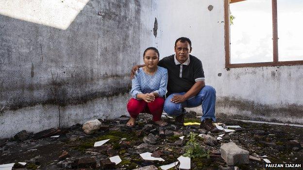 Mustafa and Rina stand among the remains of their old family home in Indonesia's Aceh province