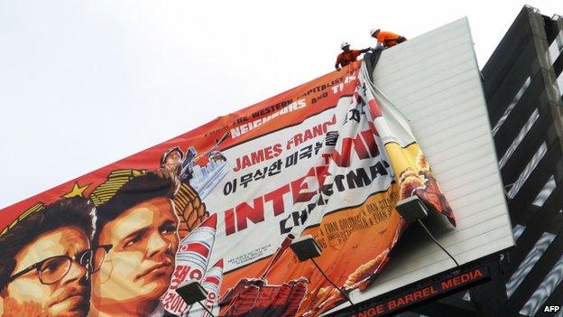 Workers remove the poster for "The Interview" from a billboard in Hollywood, California, 18 December 2014.