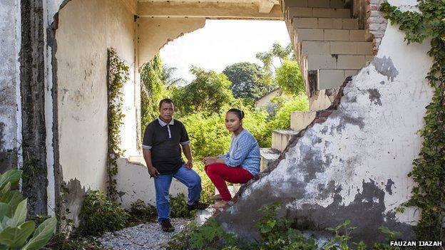 Mustafa and Rina stand among the remains of their old family home in Indonesia's Aceh province