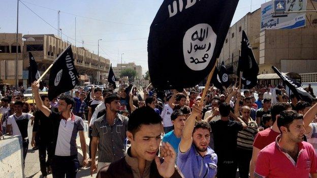 Demonstrators carry Islamic State flags in front of the provincial government headquarters in Mosul