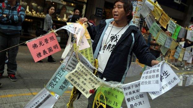 Protester cuts down a string of signs in order to allow more people to walk into the pro-democracy protest site in the Causeway Bay district of Hong Kong