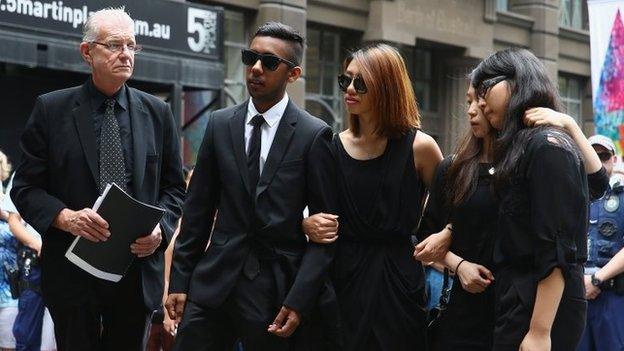 Fellow hostages Joel Herat (2nd L), Elly Chen (2nd R) and Fiona Ma (R) pay their respects at wreath laying ceremony after the funeral for Tori Johnson at Martin Place, Sydney (23 December 2014)