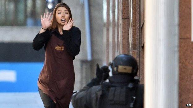 A hostage runs towards an armed police officer after escaping the cafe siege in Sydney (15 December 2014)