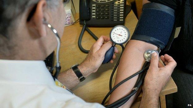 GP taking patients' blood pressure