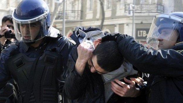 Two policemen lead away a protester in Baku in Azerbaijan