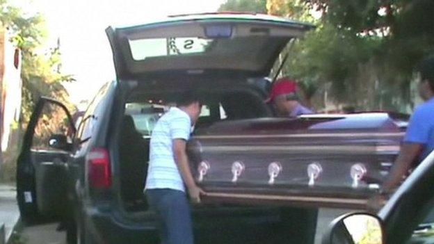 The coffin with Father Gregorio Lopez's body is loaded into a hearse