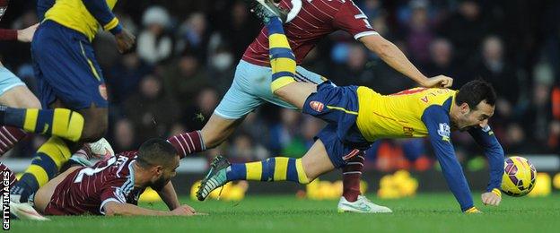 Santi Cazorla falls under a challenge from Winston Reid