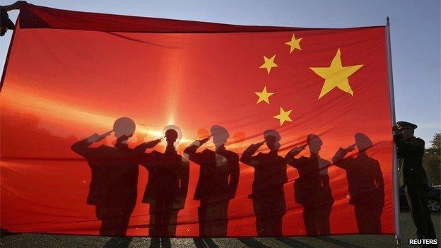 Retired paramilitary policemen, who conduct the daily national flag raising and lowering ceremony on Tiananmen Square, salute to a Chinese national flag during a farewell ceremony in Beijing on 24 November, 2014