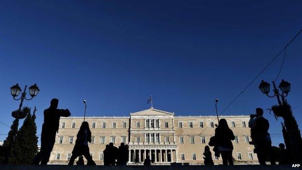 People walk in front of the Greek parliament building in Athens (17 December 2014)