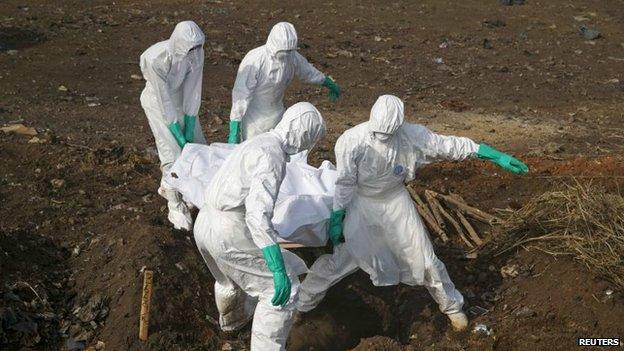 Health workers bury a body in Sierra Leone