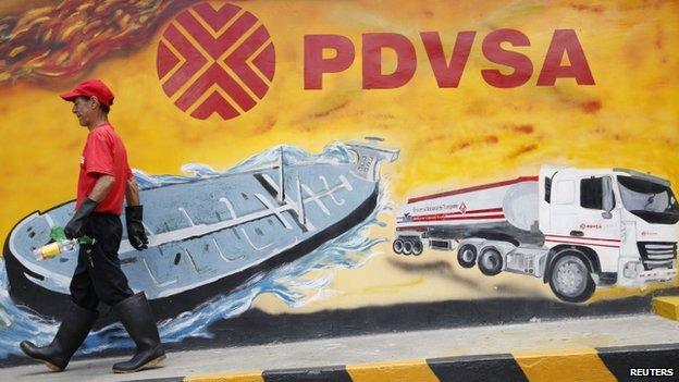 Worker pasts PDVSA mural in Caracas, Aug 2014