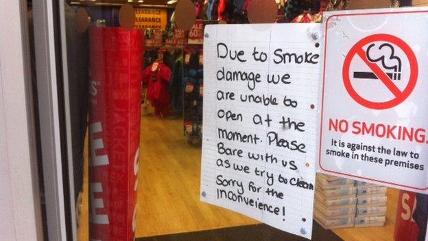 A sign in a window saying a shop has been closed due to smoke damage