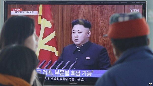 Passers-by at a Seoul train station watch Kim Jong-un's speech