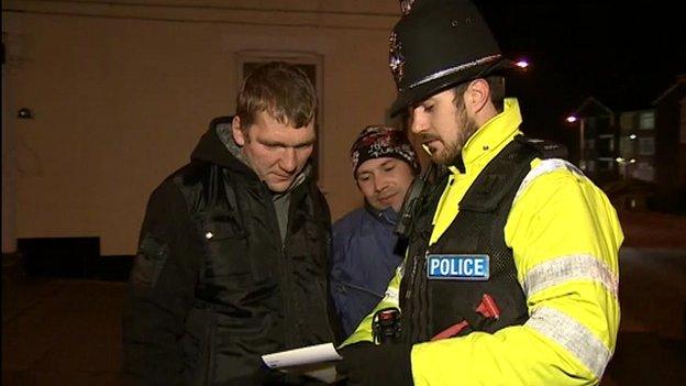 Police officers shows leaflets to members of the public