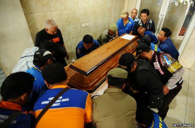 Workers carry the coffin of Meiji Thejakusuma, victim of the AirAsia flight QZ8501 crash, at a funeral home in Surabaya, Indonesia, 3 January