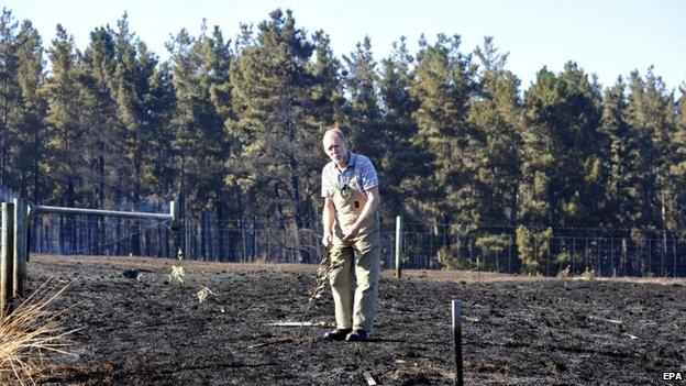 A resident checks on his property as fires continue to burn through the Adelaide Hills, in Kersbrook, near Adelaide, Australia, 4 January 2015