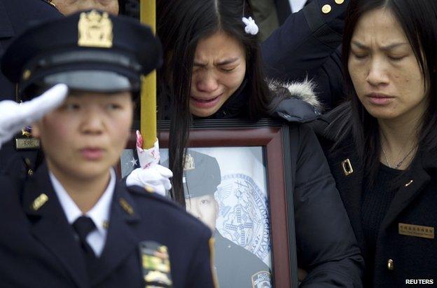 Wenjian Liu's widow, Pei Xia Chen, weeps while clutching a photo of the dead policeman at his funeral in New York, 4 January