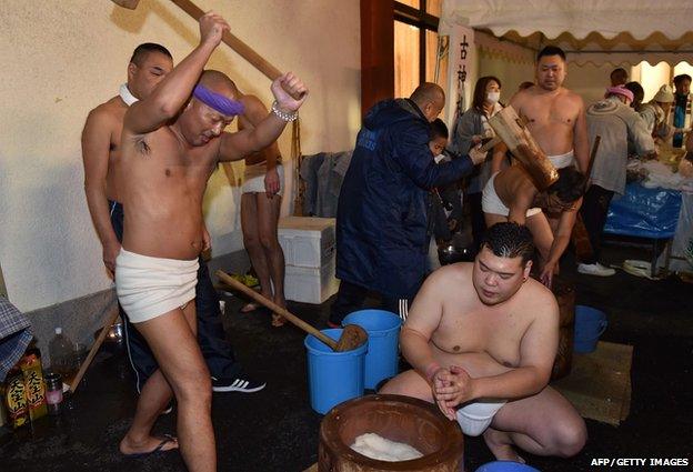 Naked men in loincloths pound steamed rice into a mochi