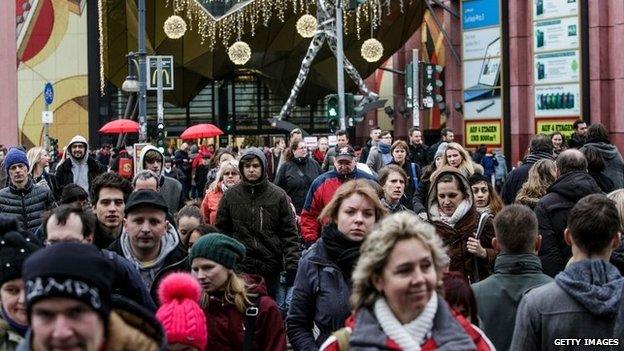 People carrying shopping bags walking in front of the Alexa Shopping Centre in Berlin