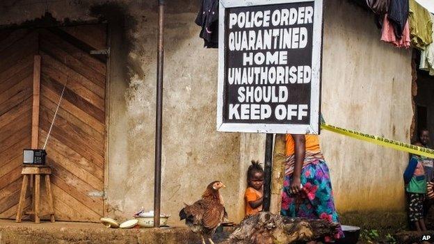 A child stands near a sign advising of a quarantined home in an effort to combat the spread of the Ebola virus in Port Loko, Sierra Leone (22 October 2014)