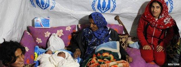 A Syrian refugee sits beside her newborn twins inside a tent at a makeshift settlement in Bar Elias in the Bekaa valley, Lebanon, 5 January 2015