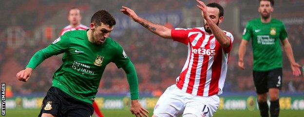 James Pearson of Wrexham runs with the ball under pressure from Marc Wilson of Stoke City during the FA Cup Third Round match