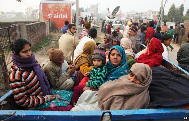 Indian villagers sit in the back of a vehicle as they flee their homes fearing firing from the Pakistan side of the border at Bainglad village in Samba sector, about 52 Kilometers from Jammu, India, Saturday, Jan. 3, 2015.