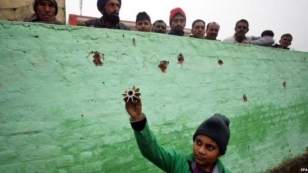 A young Indian villager holds up a piece of a mortar shell allegedly fired from the Pakistani side of the disputed Kashmir, Bainglar village in the Samba sector, some 60 km from Jammu, the winter capital of Kashmir, India, 03 January 2014