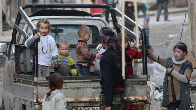 Syrian children stand in the back of a truck as they flee the contested Bab al-Hadid neighbourhood of the northern Syrian city of Aleppo following an overnight rocket attack on January 2, 2015