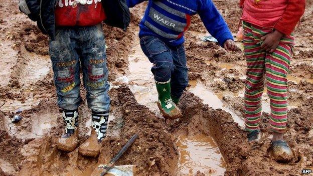 Syrian children who fled the violence in Syria's northern Raqa province play in the mud at an unofficial refugee camp in al-Saadiyeh, a village in the eastern Bekaa Valley in Lebanon, 20 December 2014