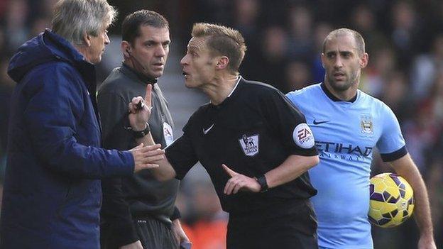 Referee Mike Jones talks with Manchester City boss Manuel Pellegrini