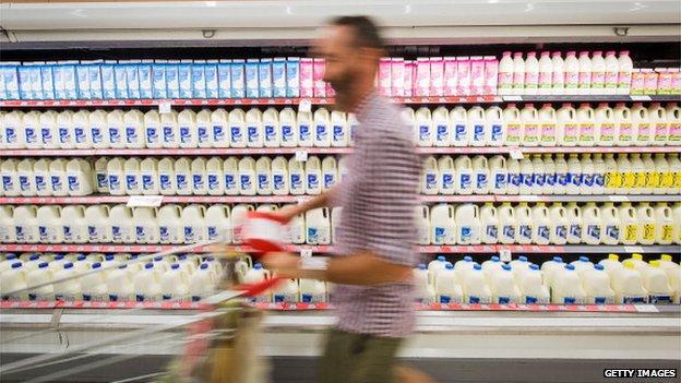 A shopper walks past bottles of milk displayed in the dairy section of a Coles supermarket, operated by Wesfarmers Ltd., in Sydney, Australia, on Tuesday, Feb. 18, 2014