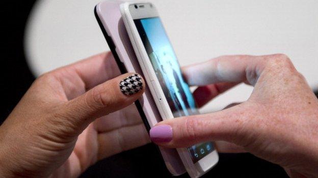 Two Motorola employees tranfer data between two of Motorola's Moto X as the American-manufactured smartphone is unveiled August 1, 2013 at a news conference in New York.