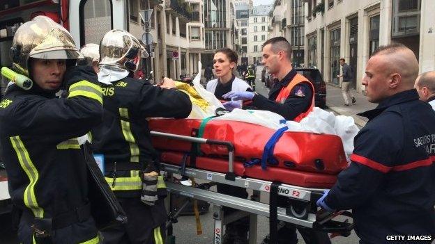 Emergency workers carry a stretcher in front of the offices of the French satirical newspaper Charlie Hebdo