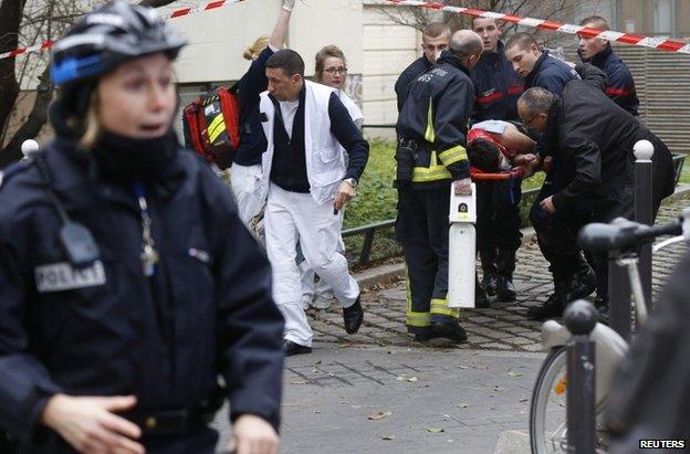 Emergency workers carry a victim on a stretcher form the scene of the shooting in Paris, 7 January