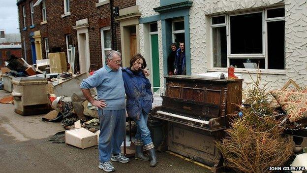 Residents of Carlisle look on as a stockpile of furniture and possessions ruined by the water awaits collection