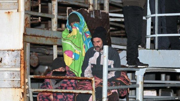 Two men wait as the cargo ship Ezadeen, carrying hundreds of migrants, arrives at the southern Italian port of Corigliano, Italy, 2 January 2015