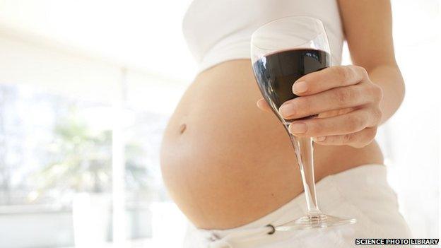 A pregnant woman with a glass of wine