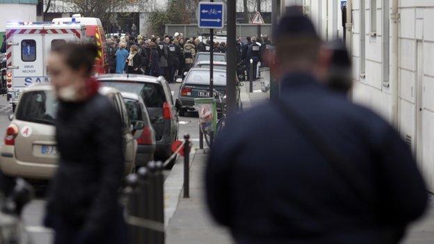 Firefighters and police officers gather in front of the offices of the French satirical newspaper Charlie Hebdo in Paris on 7 January 2015,