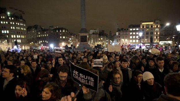 People hold up pens and posters reading "I am Charlie" in French as they take part in a vigil in London's Trafalgar Square